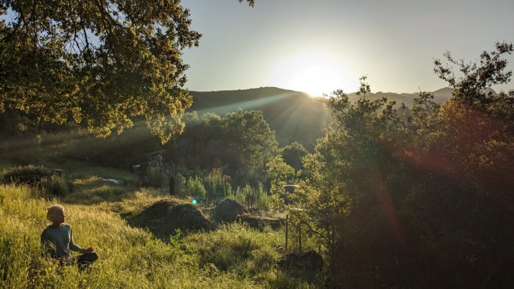 Woman meditating with a sunset in the background